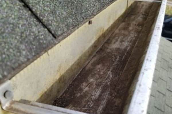 After: A close-up view of a house gutter that is free of debris and dirt after a gutter cleaning service. Small amount of dirt stains are visbile at the very bottom of the gutter channel.