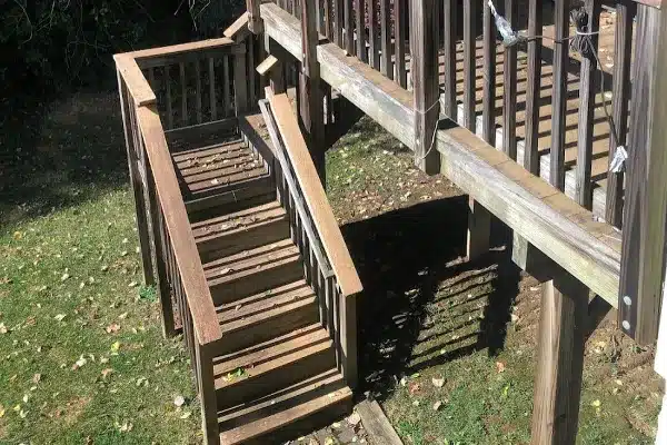 Before: A wooden staircase leads down from a raised deck to a grassy area, surrounded by trees and fallen leaves.