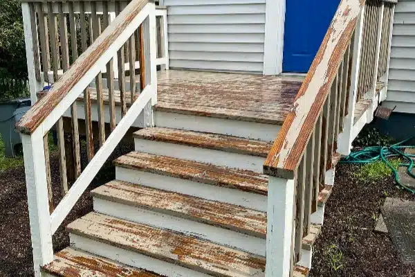 Before: Weathered wooden steps leading to a house with a blue door, surrounded by gravel and a garden hose on the ground.