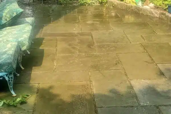 Before: A stone patio with a patterned green lounge chair and scattered leaves, illuminated by sunlight.