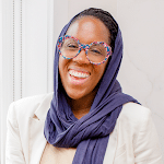 Person smiling, wearing colorful glasses and a dark scarf, against a light background.
